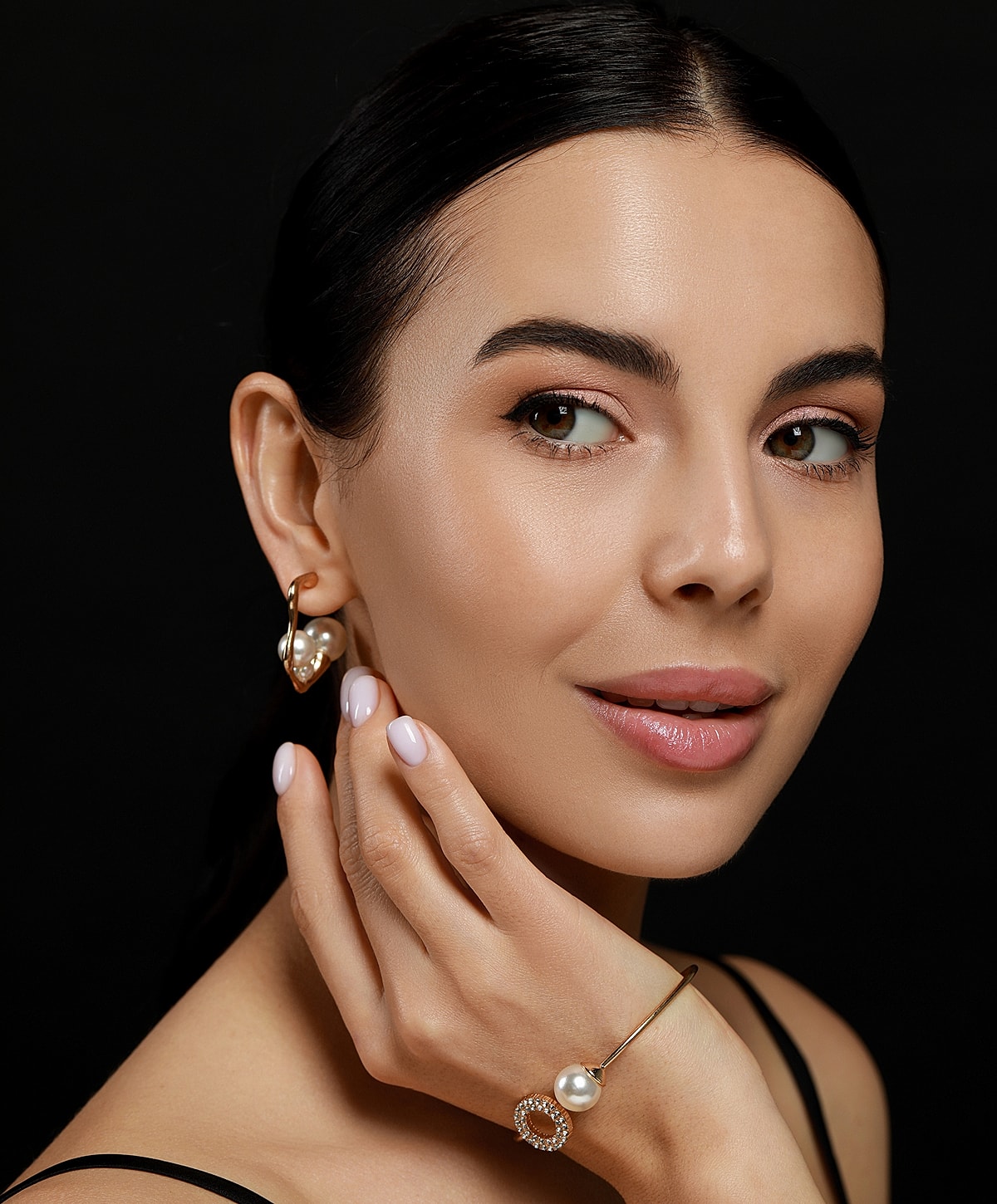 Model showcasing elegant jewelry against black background.