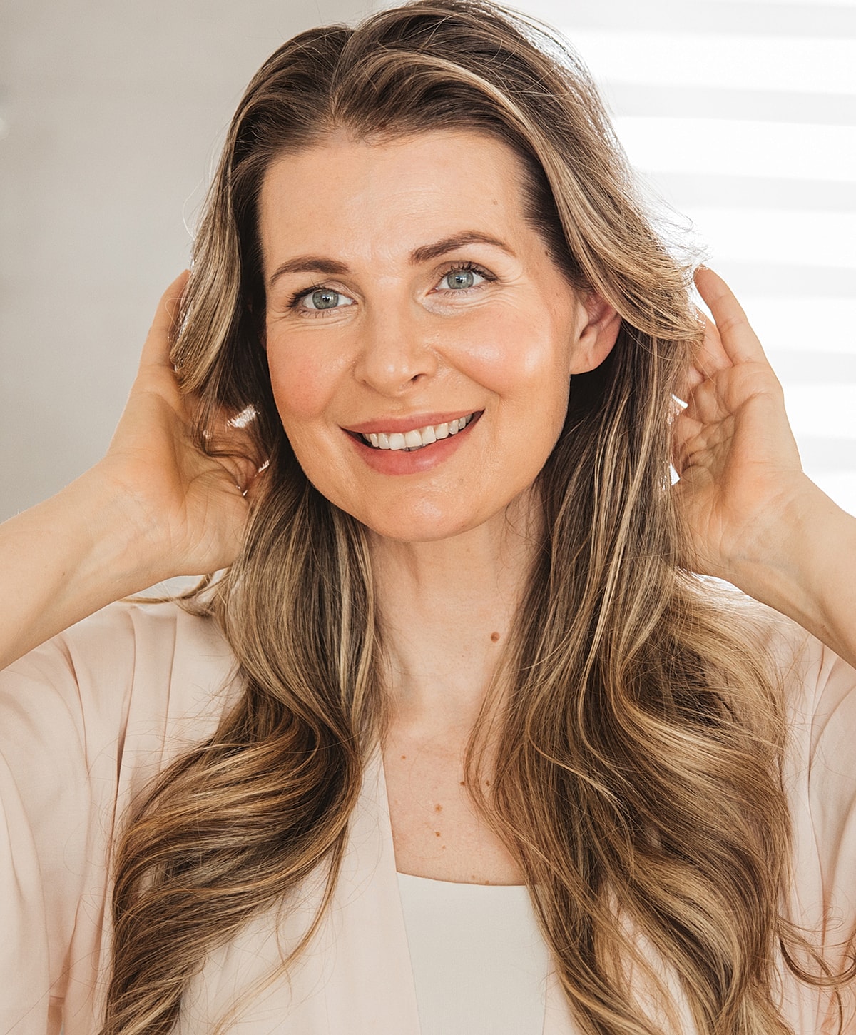 Smiling woman with long, styled hair indoors.