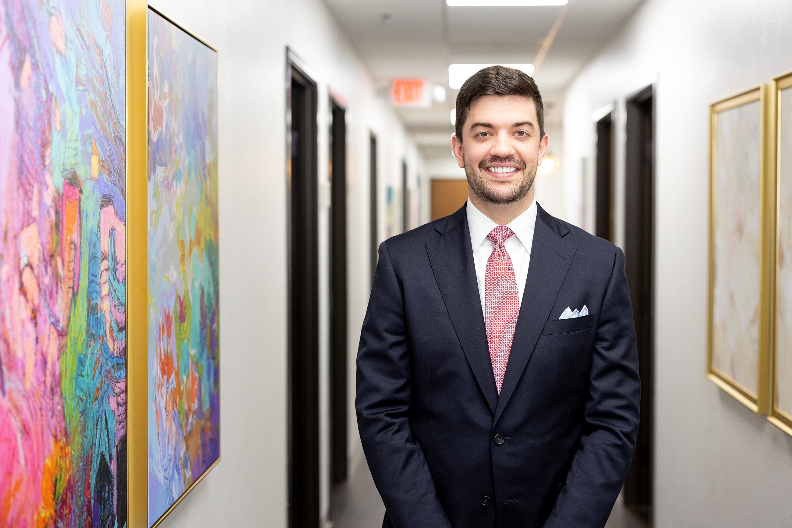 Man in suit standing in hallway with artwork.