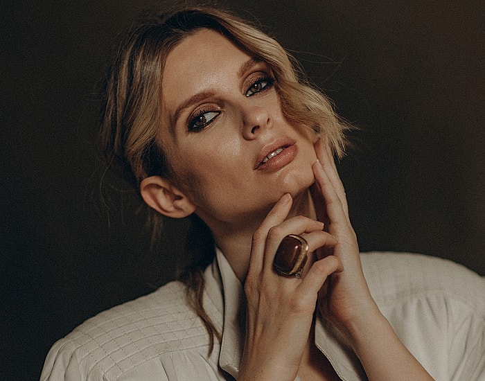 Woman posing with hands on face, stylish ring.