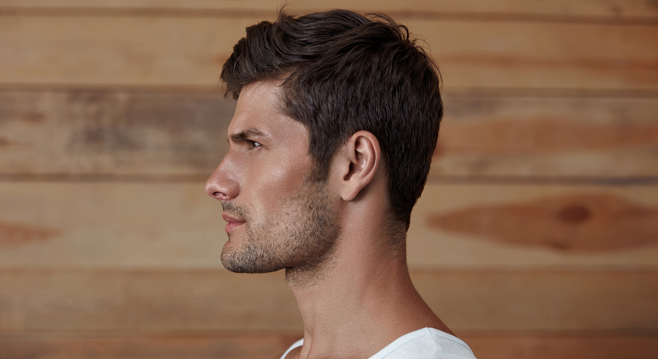Man in profile against wooden background.