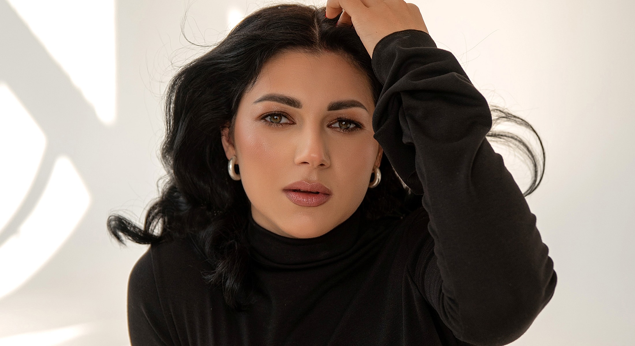 Woman with dark hair in a black turtleneck.